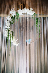 Arch decorated with a composition of white flowers and greenery in the banquet hall. Decor in the banquet area at the wedding party.