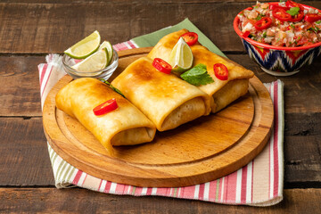 Traditional chimichanga Mexican snack on a wooden table.