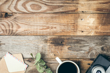 Wooden vintage background with a letter, a cup of coffee and a retro camera.