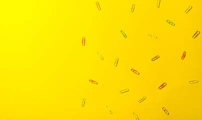 Pattern of multicolored paper clips on grey background. Back to school. Office, business, paperwork, education concept.