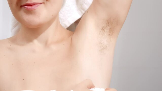 Closeup of young woman covered in white towel showing her long dark armpit hair. Concept of beautiful female, natural beauty, feminity and body hair