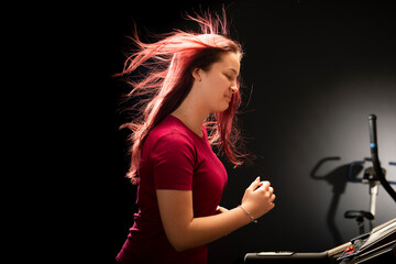 A young woman in the gym is running on a treadmill