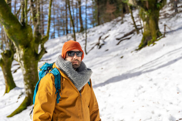 Fototapeta na wymiar Portrait of a hiker with a backpack on a snow trekking, winter adventures in a beech forest