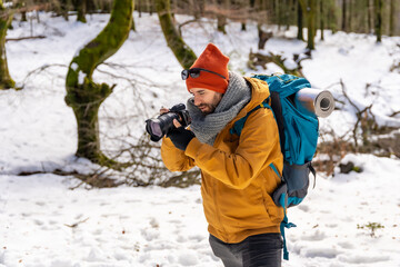 Fototapeta na wymiar Photographer enjoying taking photos in winter on the mountain with snow, winter hobbies