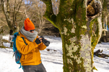 Fototapeta na wymiar Photographer taking winter photos in the mountains with snow, winter hobbies, beech forest
