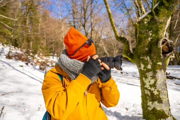 Fototapeta na wymiar Photographer taking winter photos in the mountains with snow trekking with a backpack
