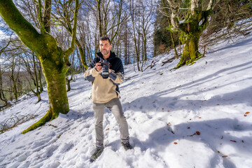 Fototapeta na wymiar Portrait of a photographer man in snow enjoying winter photography in a beech forest