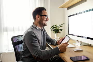 A happy social media marketer uses high tech gadgets at home office.