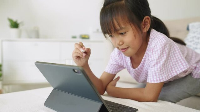 Education. Asian little girl learning and drawing with the online teacher on tablet digital