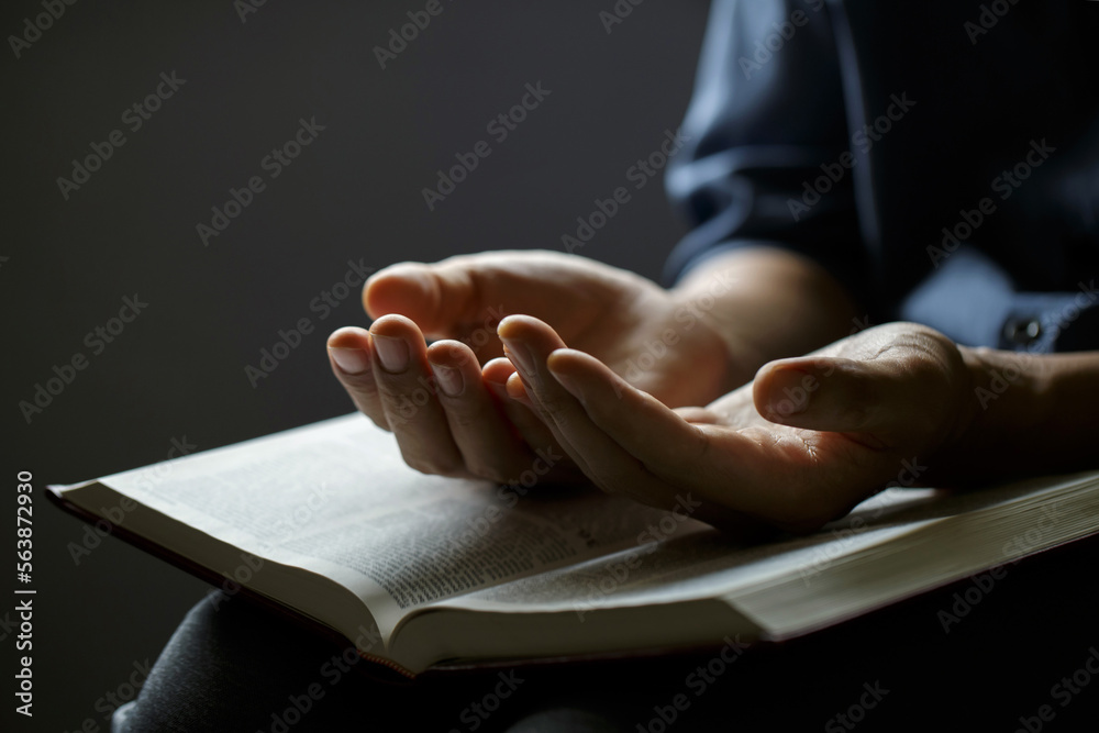 Wall mural praying hands, man prays with hands together over a holy bible, in the christian concept of faith, s