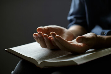 Praying hands, Man prays with hands together over a Holy Bible, In the Christian concept of faith,...