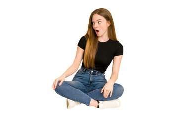 Young redhead woman sitting on the floor cut out isolated being shocked because of something she has seen.