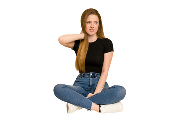 Young redhead woman sitting on the floor cut out isolated touching back of head, thinking and making a choice.