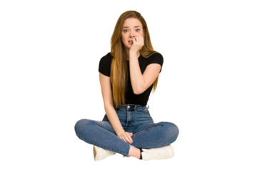 Young redhead woman sitting on the floor cut out isolated biting fingernails, nervous and very anxious.