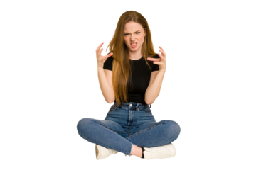 Young redhead woman sitting on the floor cut out isolated upset screaming with tense hands.