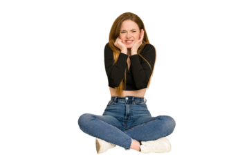 Young redhead woman sitting on the floor cut out isolated suspicious, uncertain, examining you.