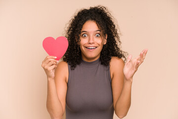 Young african american woman holding a heart for valentines day isolated receiving a pleasant...