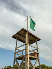 Lifeguard tower with green flag on the beach. Safe beach for swimming.