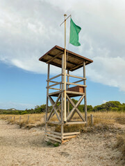 Lifeguard tower with green flag on the beach. Safe beach for swimming.