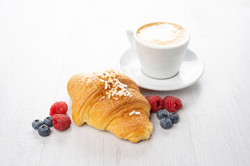 cappuccino cup with brioches croissant with red fruits and strawberries