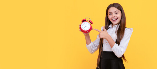 smiling child in school uniform point finger on alarm clock showing time, back to school. Teenager child with clock alarm, horizontal poster. Banner header, copy space.