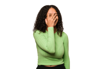 Young african american curly woman isolated blink at the camera through fingers, embarrassed covering face.