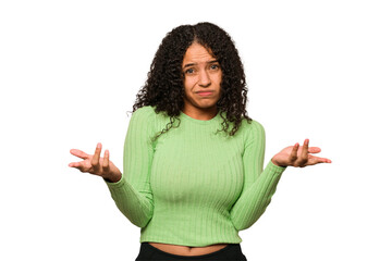 Young african american curly woman isolated doubting and shrugging shoulders in questioning gesture.