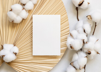 Blank card on dried palm leaf with cotton flowers top view, wedding mockup