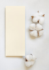 Blank card with cotton flowers top view on white, wedding mockup
