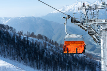 Empty bright orange ski chair lift in mountains in winter against the backdrop of snow Alpine...