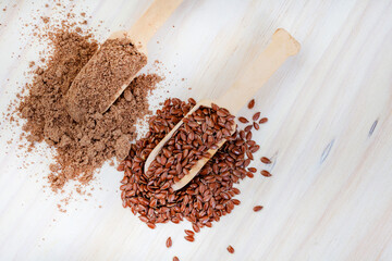 scoops of flax seeds and flax seed powder on light wood