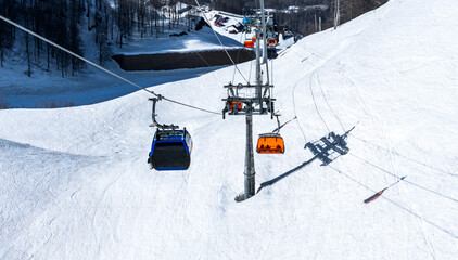 Empty bright orange ski chairs lift and lift cabin in mountains in winter against the backdrop of...