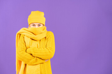 Arms crossed woman wearing winter clothes and shivering isolated on purple background