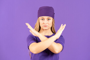 Young feminist woman making negation gesture with hands isolated on purple background. Feminism,...