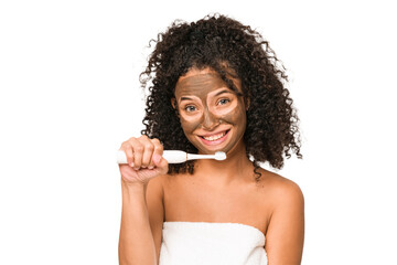 Young african american woman toothbrushing and applying herself a facial mask isolated
