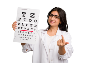 Young indian oculist woman holding an eye chart paper cut out isolated pointing with finger at you as if inviting come closer.