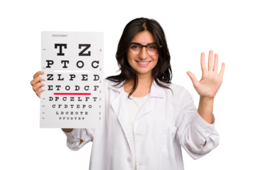 Young indian oculist woman holding an eye chart paper cut out isolated smiling cheerful showing number five with fingers.