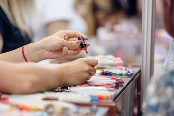 Closeup photo of saleswoman showing nail polish colors at cosmetics store