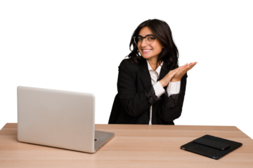 Young indian woman in a table with a laptop and tablet isolated feeling energetic and comfortable, rubbing hands confident.