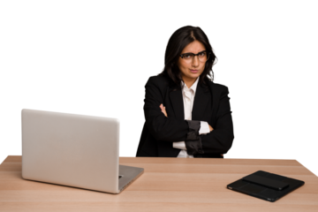 Young indian woman in a table with a laptop and tablet isolated frowning face in displeasure, keeps arms folded.