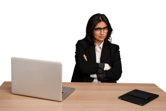 Young indian woman in a table with a laptop and tablet isolated frowning face in displeasure, keeps arms folded.
