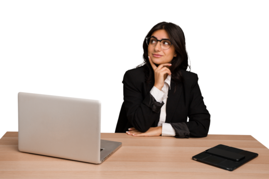 Young indian woman in a table with a laptop and tablet isolated contemplating, planning a strategy, thinking about the way of a business.