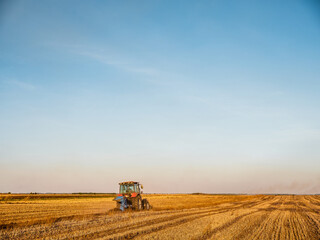 Tractor plowing and preparing stubble field for crop cultivation