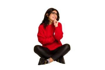 Young indian woman sitting on the floor cut out isolated relaxed thinking about something looking at a copy space.