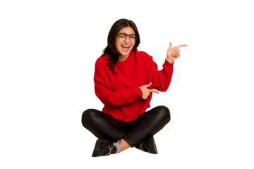 Young indian woman sitting on the floor cut out isolated pointing with forefingers to a copy space, expressing excitement and desire.