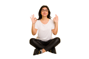 Young indian woman sitting on the floor cut out isolated relaxes after hard working day, she is performing yoga.