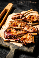 A rack of grilled lamb on a cutting board on paper. 