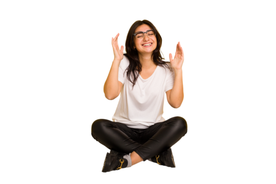 Young indian woman sitting on the floor cut out isolated joyful laughing a lot. Happiness concept.