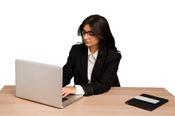 Young indian woman in a table with a laptop and tablet using a mobile phone isolated