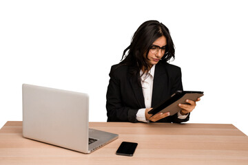 Young indian woman in a table with a laptop and tablet using a mobile phone isolated